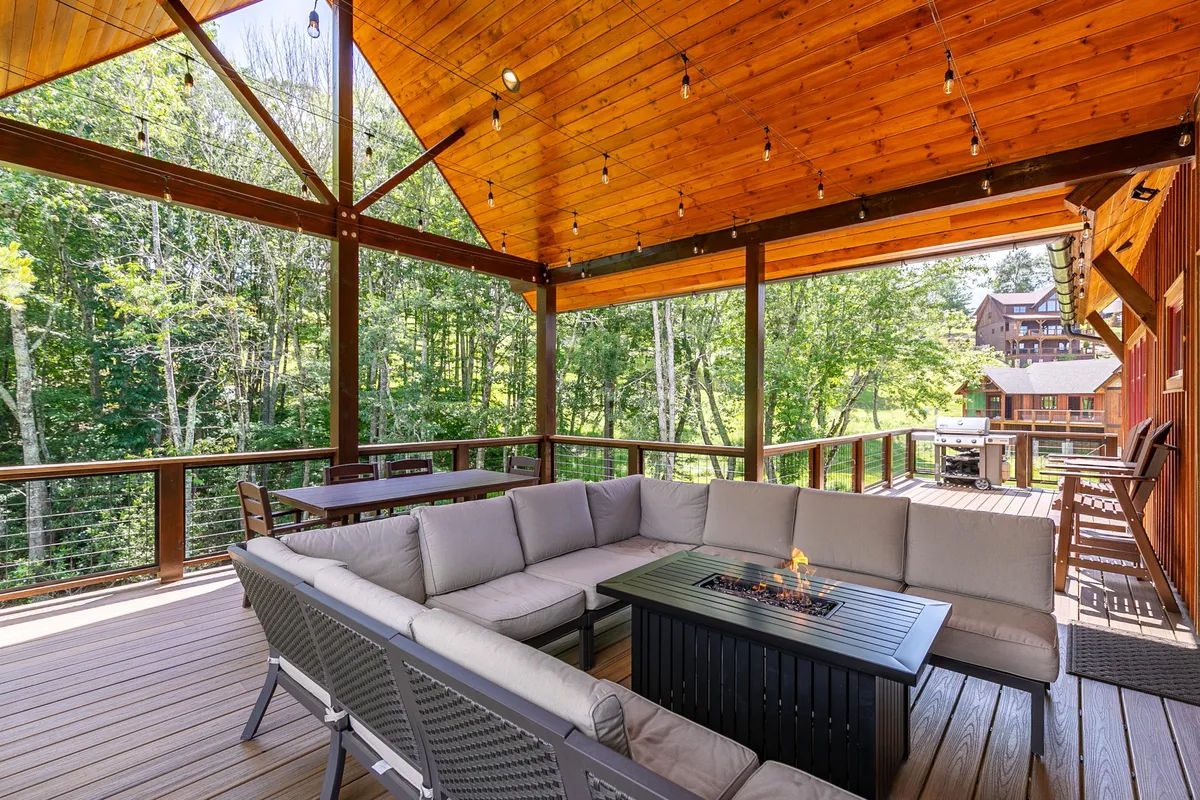 This image presents a spacious outdoor seating area with a fire pit, wooden beams, and abundant greenery. It suggests opportunities for gatherings, relaxation after a day of adventure, and seamless indoor-outdoor living.