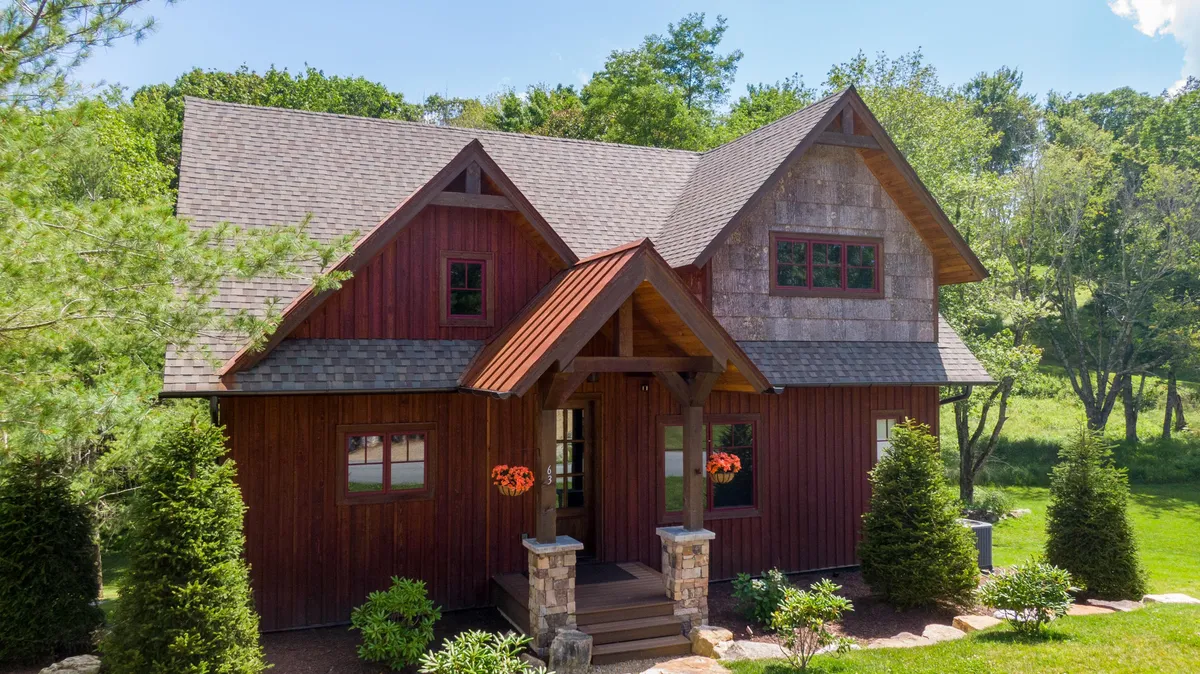A cozy and inviting front porch framed by stone accents and surrounded by greenery. The porch is designed for family gatherings, outdoor relaxation, and social connection, providing a seamless transition between indoor comforts and the natural world outside.