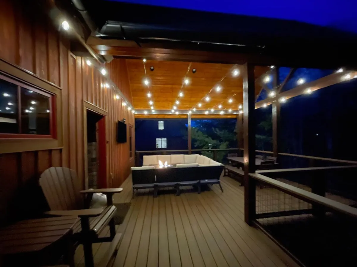 An intimate exterior set-up with string lights overhead, a fire pit, and comfortable outdoor seating arranged for evening relaxation. The ambiance is warm, ideal for storytelling or enjoying the starry sky.