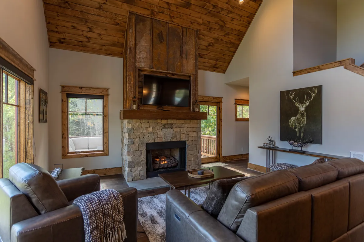 A cozy lounge area with a stone fireplace, large windows, and comfortable seating. The wall art and plush furnishings add a playful yet relaxing vibe, making it ideal for gathering, watching TV, or simply unwinding after a busy day.